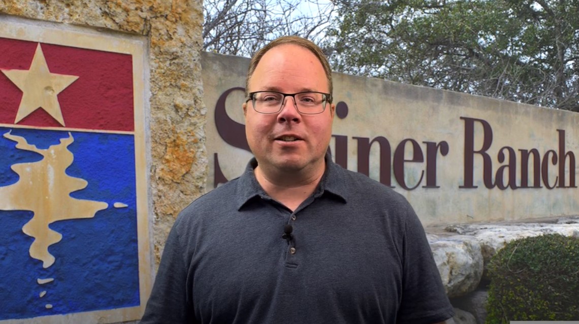 Chief Executive Officer and General Manager, Jason Homan, standing by the Steiner Ranch sign, explaining the importance of the Pressure Regulating Valve (PRV) and its necessity for the area's water system.