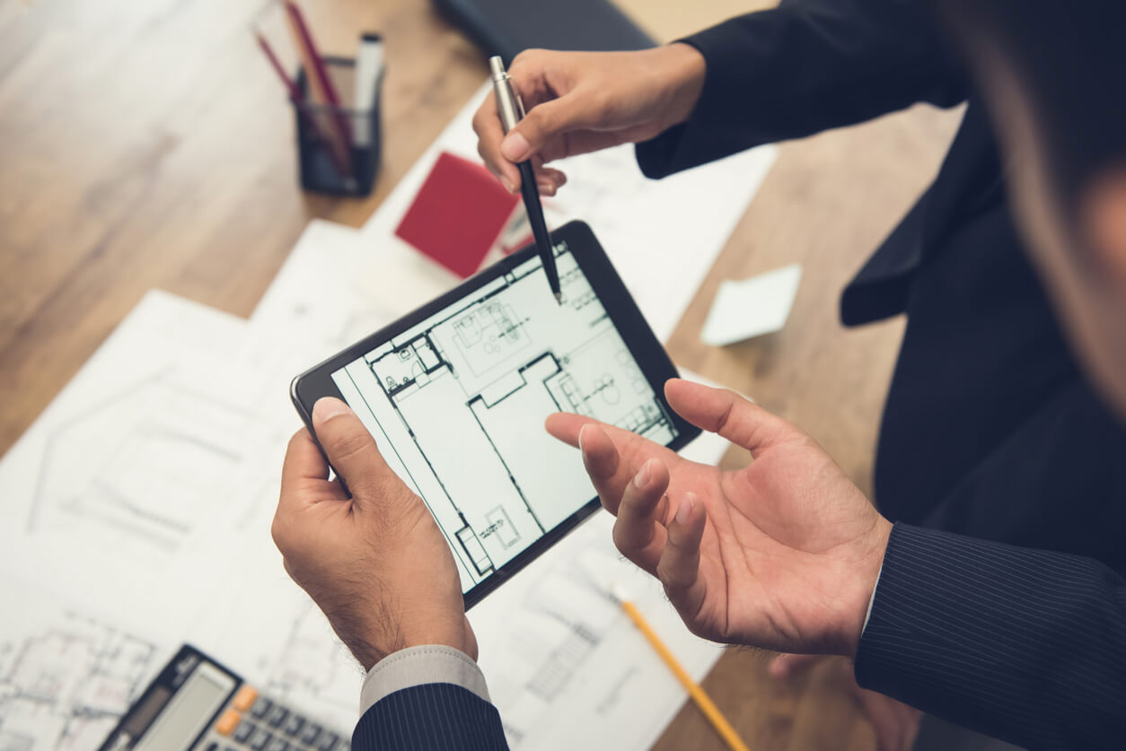 Professional realtor and appraiser reviewing a blueprint of a home, discussing property details.